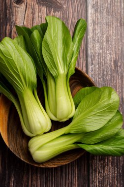 Celery cabbage or peach choi, asian baby salad leaves on wooden background, top view