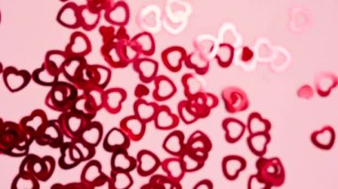 Red hearts confetti on pink background, rotating, selective focus, Valentines Day.