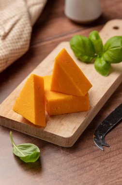 Cheddar orange cheese slices, wooden background, copy space