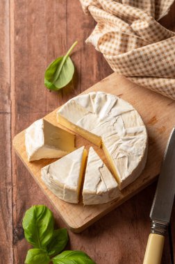 Brie, soft cheese slices on cutting board. 