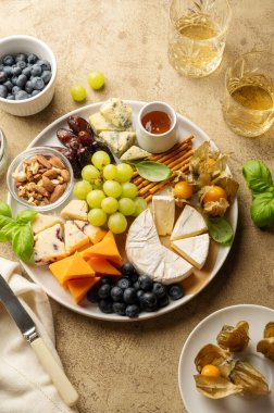 CheCheese board with fruits, nuts and snacks. Warm background