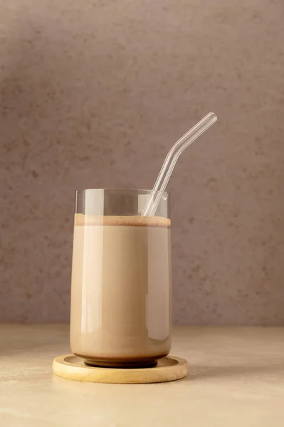 Glass of chocolate shake drink with protein powder scoop and glass straw