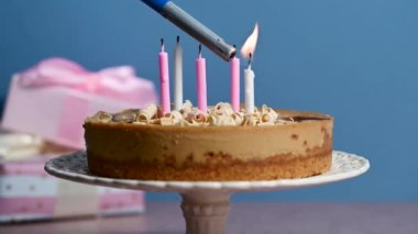 Pasta tezgahında mum yakmak, hediye kutuları, renkli mavi arka plan. Gerçek zamanlı 4 bin dolar, görüntüler.