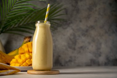 Bottle of mango, banana and yoghurt smoothie with a straw