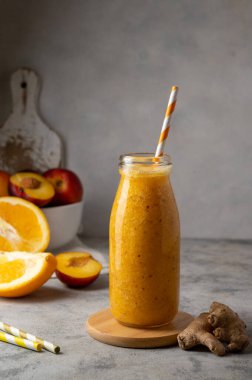 Bottle of fresh orange smoothie made with peach, ginger and orange, healthy drink