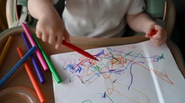 Cute toddler with crayons, colourful pencils. Soft selective focus