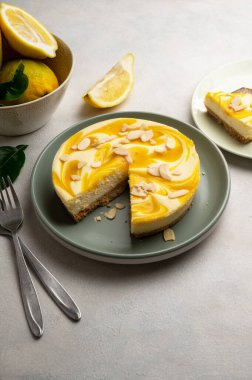 Lemon cheesecake tart or pie, with fresh lemons. Grey background.