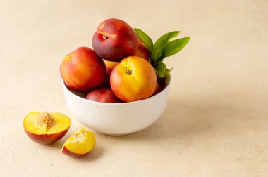 Whole nectarine peaches, fresh red fruits in a bowl. Neutral background
