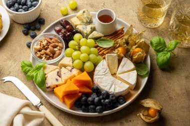 Cheese board with fruits, nuts and snacks. Warm background