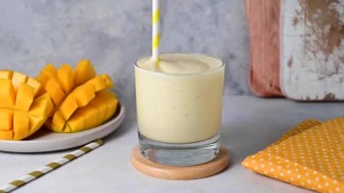 Mango, muz ve yoğurt karışımı bardakta, buzlu içeceği pipetle karıştırıyorum.