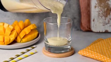 Pouring mango, banana and yoghurt smoothie in glass, healthy eating concept