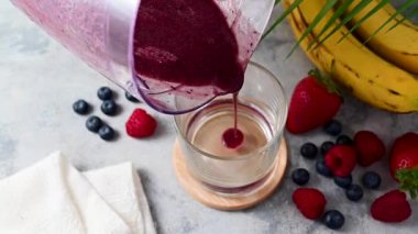 Pouring smoothie in a glass. Strawberry, banana, blueberry thick smoothie