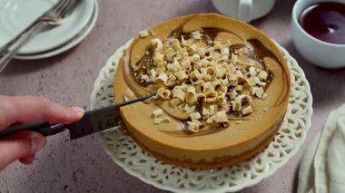 Cutting a slice of caramel cheesecake, top view, real time video. High quality 4k footage