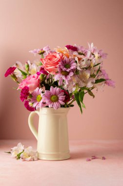 Beautiful fresh spring flowers. Pink bouquet of flowers in vase, on pink background