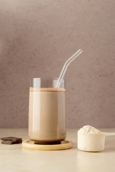 Glass of protein shake drink with protein powder scoop and glass straw