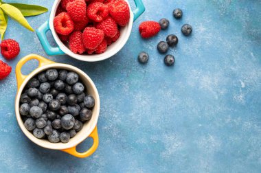 Fresh berries. Blueberry and raspberry in ceramic bowls. Colourful fruit, food background, top view