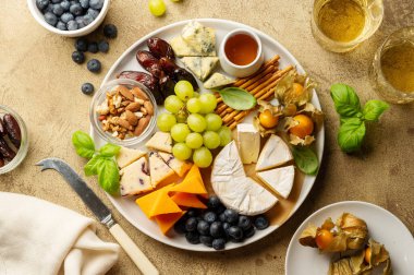 Cheese platter with fruits, nuts and snacks. Warm background
