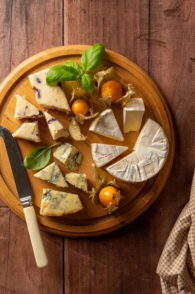 Top view cheese board with blue cheese, cheddar and fruit cheese, rustic wooden background