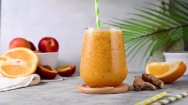 Mixing orange smoothie made with peach, ginger and orange, healthy drink