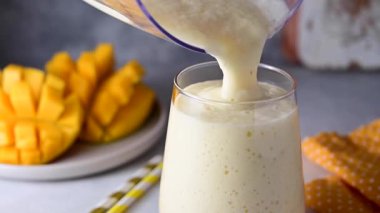Mango muzlu smoothie bardağa dökülüyor, sağlıklı beslenme konsepti. 