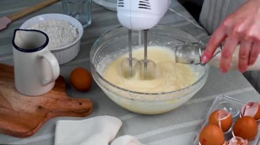 El çırpıcı kullanan, tatlı pişiren kadın elleri. Süt eklemek ve kek için hamur karıştırmak.