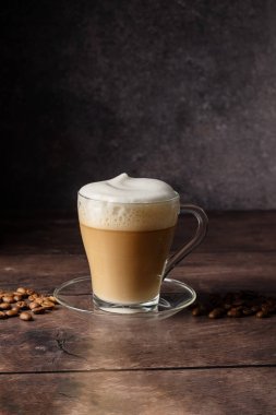 Cups of coffee drink, latte or mocha with milk foam. Glass mug, dark wooden background.