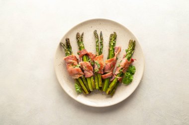 Wrapped asparagus with bacon in a plate. Top view.