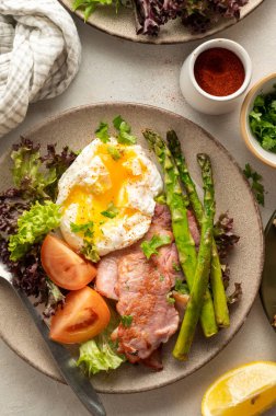 Healthy breakfast - asparagus wrapped with bacon, benedict poached egg and salad