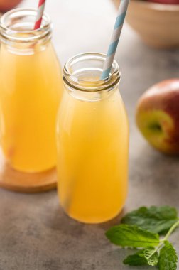 Elma suyu şişeleri, taze kırmızı elmalar, ahşap arka plan.