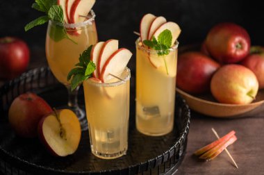 Taze kırmızı elmalı, koyu arkaplanlı üç bardak taze elma kokteyli..