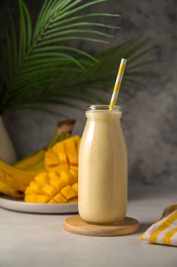 Bottle of mango, banana and yoghurt smoothie with a straw