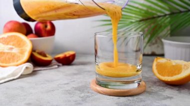 Pouring fresh orange smoothie, peach, ginger and orange blended healthy drink