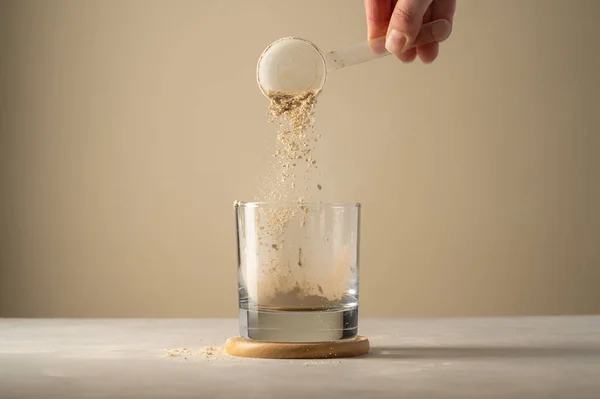Pouring protein powder from scoop, in glass a glass. Making protein drink