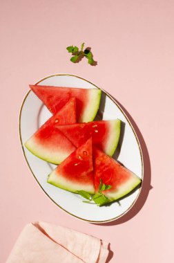 Tabakta taze karpuz dilimleri, üst manzara, pembe arka plan.