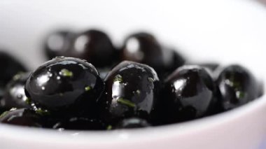 Macro, siyah zeytinleri beyaz kaseye koy. Lezzetli, marine edilmiş zeytin. Yiyecek.