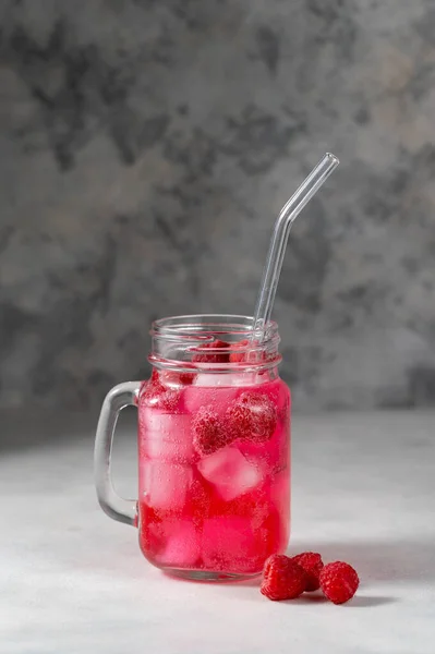 Raspberry refreshing lemonade in mason jar with glass straw, summer cold drink