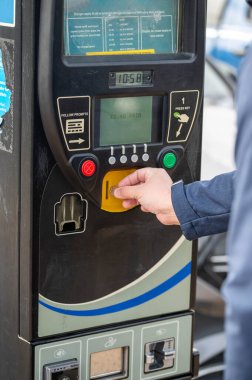 28 Mart 2023. Corby, Birleşik Krallık. Park ücretini ödemek için parkmetreye bozuk para koyan bir adam.