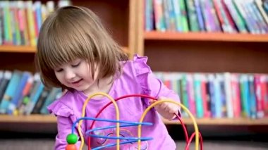 Eğitici, tahta tel oyuncaklarla oynayan beyaz, tatlı bir kız kütüphanede, Montessori oyuncağı. Gerçek zamanlı video