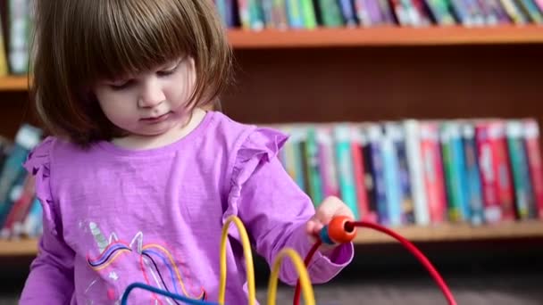 幼児の女の子は彼の床で遊んで 教育と 図書館での木製のワイヤーおもちゃ Montessoriのおもちゃ — ストック動画
