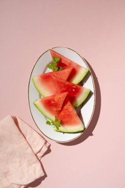 Tabakta taze karpuz dilimleri, üst manzara, pembe arka plan. Yaz Yemekleri