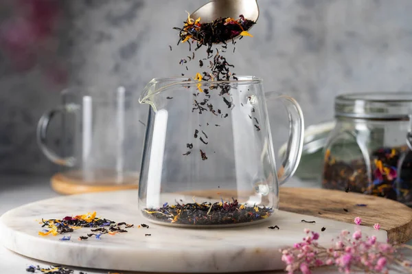 Adding loose black leaf tea to glass tea pot. Making tea
