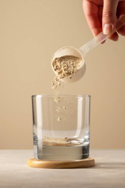 Bardakta, kepçeden protein tozu dök. Protein içeceği