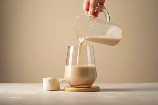 Protein powder and drink. Pouring chocolate drink in a glass
