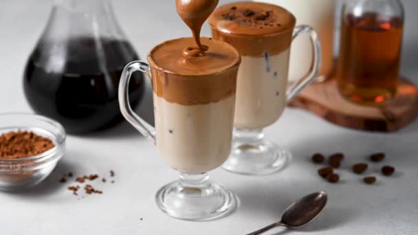 ダルゴナコーヒー アイスホイップコーヒーとミルクでガラスカップ リアルタイムビデオ — ストック動画
