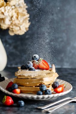 Çilekli, yabanmersinli ve pudra şekerli Belçika ev yapımı waffle 'lar. Koyu arkaplan.