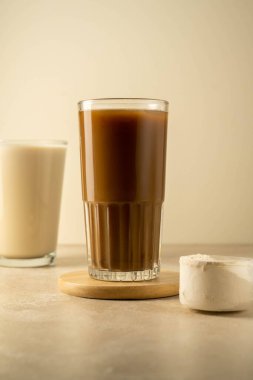 Bir kepçedeki protein tozu ve bir bardak protein içeceği. Vücut geliştirme, fitness sporu, sağlık ve beslenme