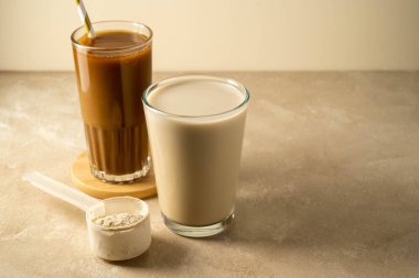 Bir kepçedeki protein tozu ve bir bardak protein içeceği. Vücut geliştirme, fitness sporu, sağlık ve beslenme