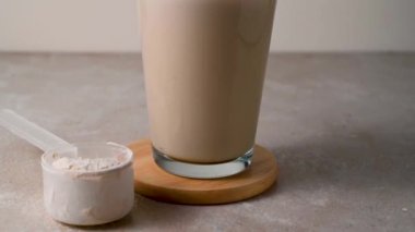 İki bardak protein içeceğiyle bir kepçedeki protein tozu. Vücut geliştirme, fitness sporu, sağlık ve beslenme
