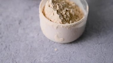 İki bardak protein içeceğiyle bir kepçedeki protein tozu. Vücut geliştirme, fitness sporu, sağlık ve beslenme