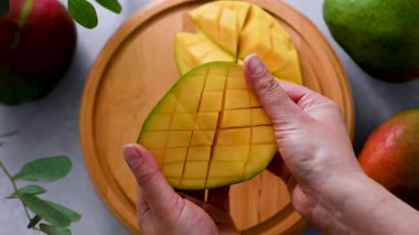 Kesilmiş mango meyvesini ikiye bölmüş bir kadın.